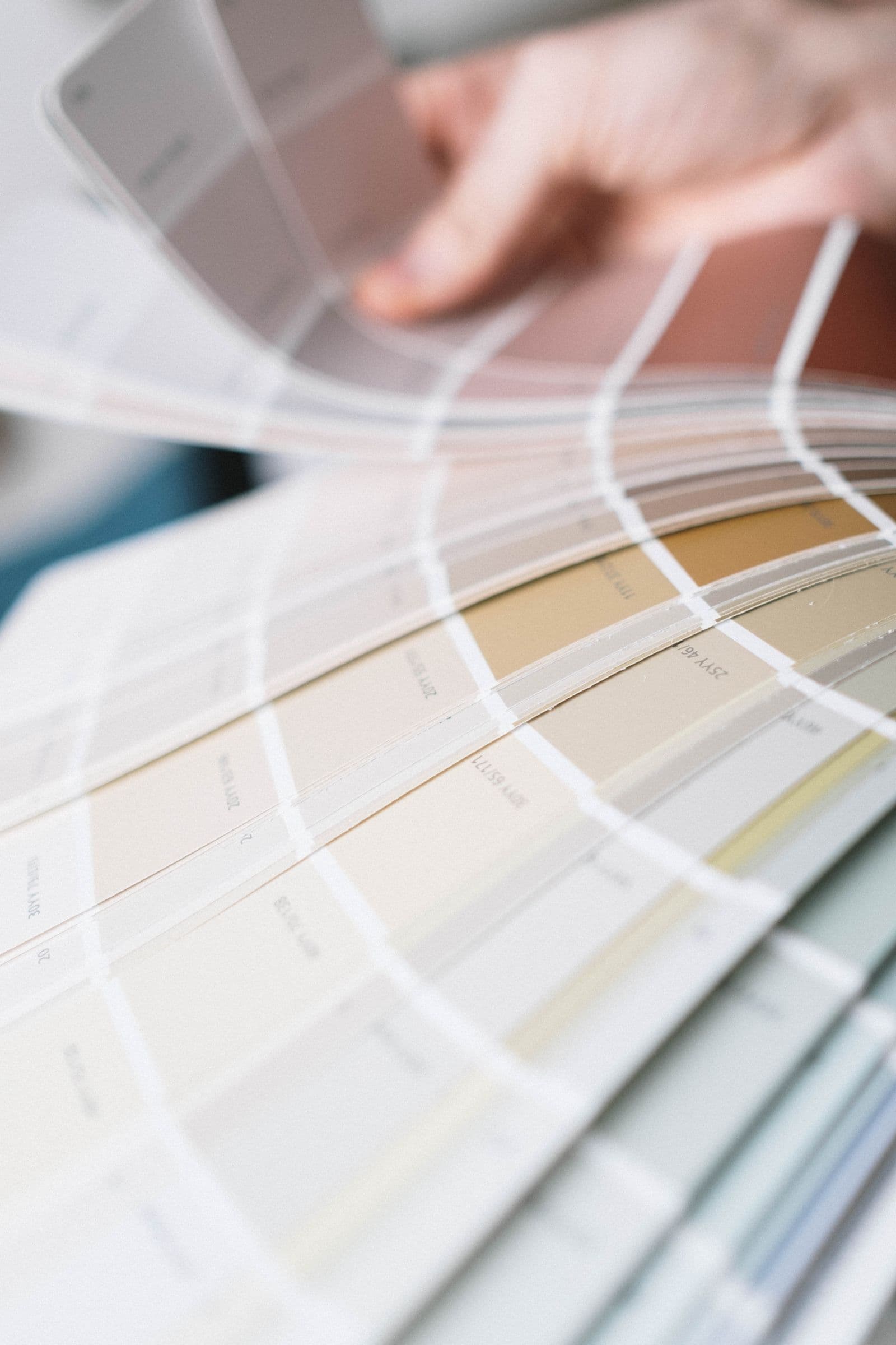 A fan deck of paint colour chips opened across warm neutral tones