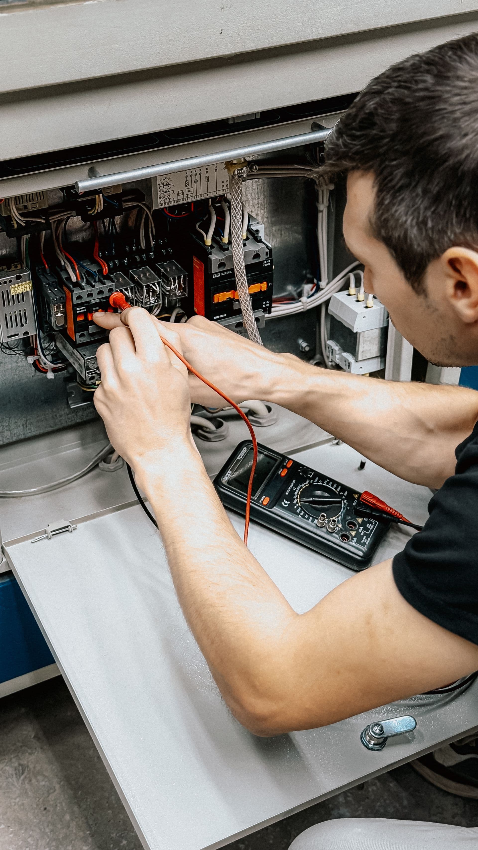 Electrician testing a residential switchboard with a multimeter